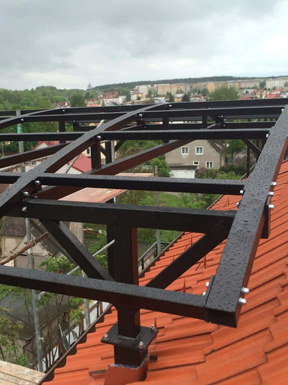 Skręcana stalowa rama zadaszenia Damet na słupie z blachą podstawy, osadzona na dachu